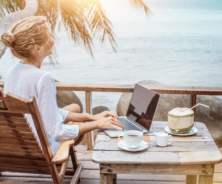 laptop and coffee overlooking a tropical beach